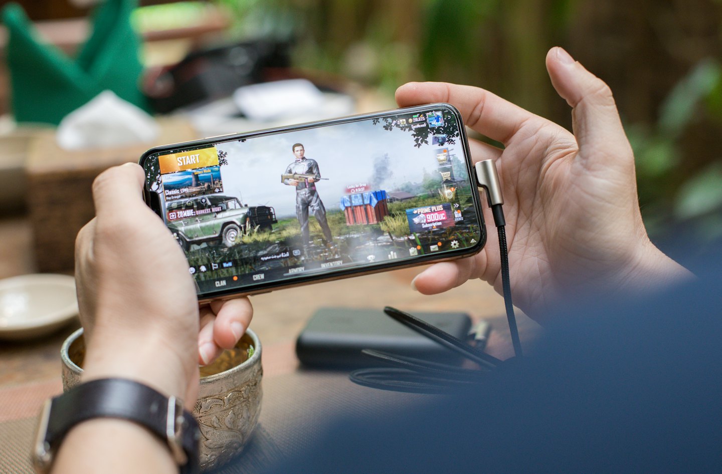 Hands holding a smartphone horizontally playing a video game.